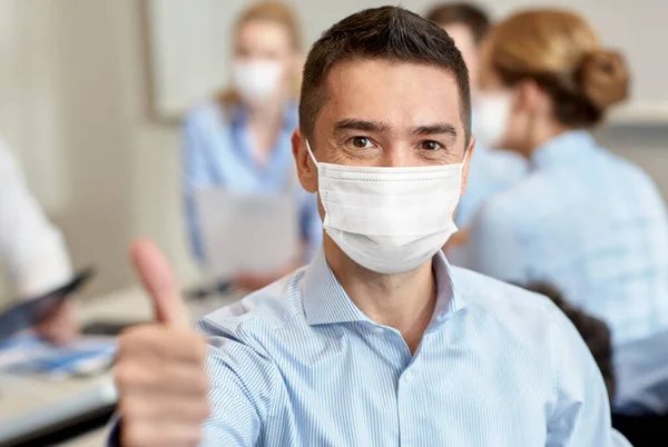 Zakenman in masker tonen duimen omhoog op kantoor — Stockfoto