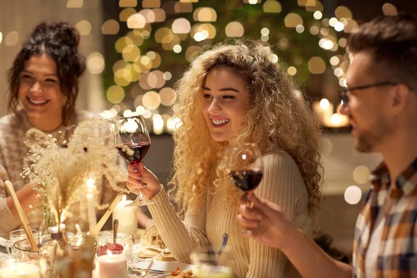 Amigos felizes bebendo vinho tinto na festa de Natal — Fotografia de Stock