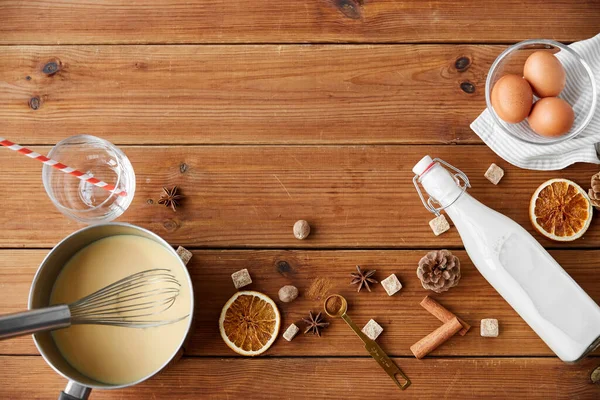 Pot with eggnog, ingredients and spices on wood — Stock Photo, Image