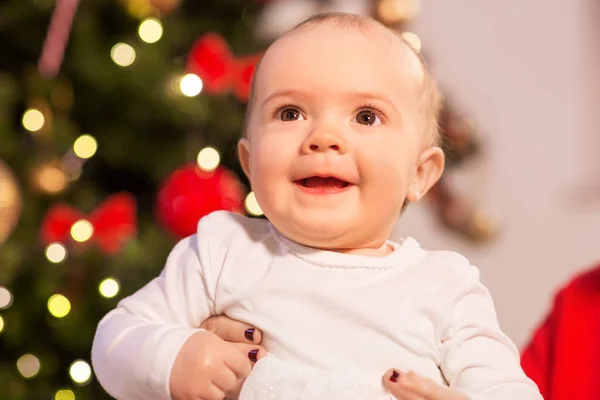 Sorrindo bebê menina sobre luzes de árvore de natal — Fotografia de Stock