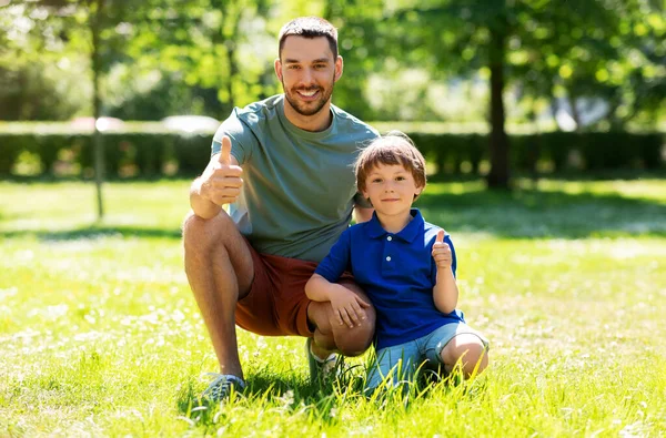 Feliz padre sonriente y pequeño hijo en el parque de verano —  Fotos de Stock
