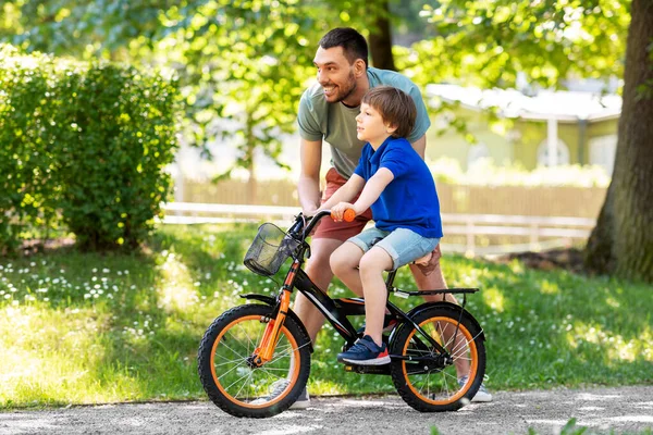 Padre enseñando a su hijo a montar en bicicleta en el parque — Foto de Stock