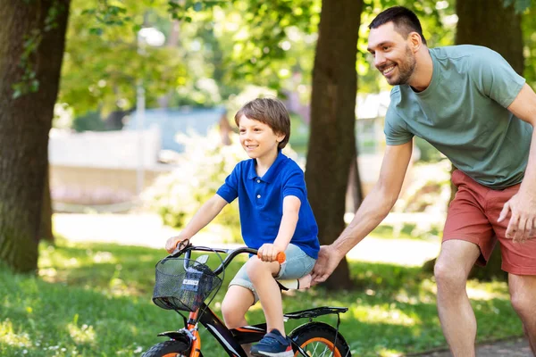 Padre enseñando a su hijo a montar en bicicleta en el parque — Foto de Stock