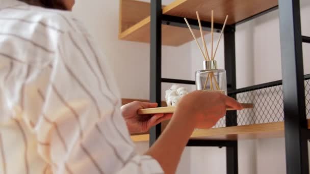 Kobieta umieszczając aromatyczny dyfuzor trzciny do półki do domu — Wideo stockowe