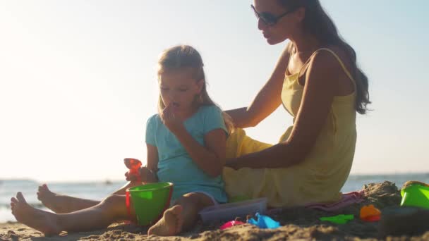 妈妈和女儿在海滩上玩玩具 — 图库视频影像