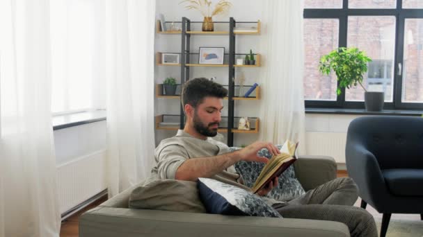 Άνθρωπος ανάγνωση βιβλίο και πίνοντας καφέ στο σπίτι — Αρχείο Βίντεο