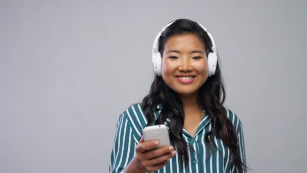 Aziatische vrouw in hoofdtelefoon luisteren naar muziek — Stockvideo