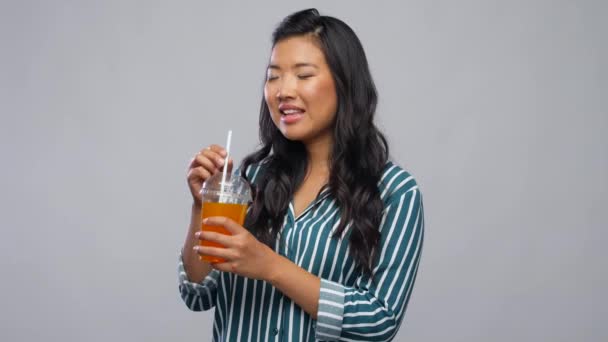 Женщина пьет сок из пластиковой чашки с соломой — стоковое видео