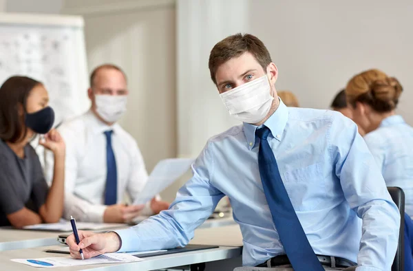 Бизнесмен в защитной маске на работе — стоковое фото