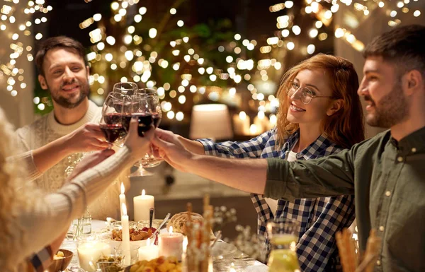 Happy friends drinking red wine at christmas party Royalty Free Stock Photos