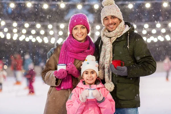 Lycklig familj dricka varmt te på skridskobana — Stockfoto