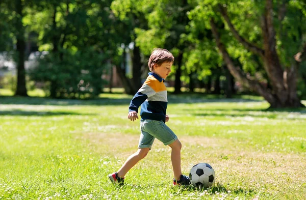 Niño feliz con pelota jugando al fútbol en el parque — Foto de Stock