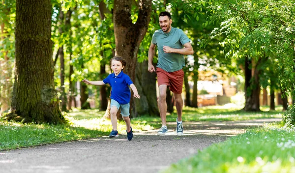 Feliz padre e hijo compiten en correr en el parque — Foto de Stock