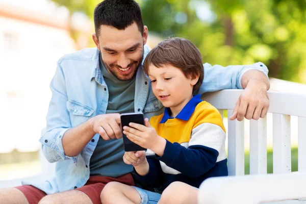 父亲和儿子在公园里拿着智能手机 — 图库照片