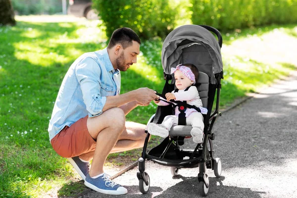 Šťastný otec s dítětem v kočárku v letním parku — Stock fotografie