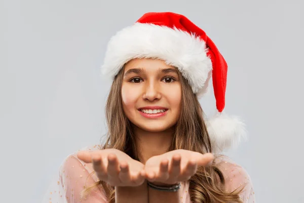 Happy teenage girl in santa hat holding something — Stock Photo, Image
