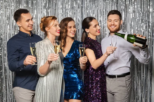 Amigos vertiendo champán a las copas en la fiesta — Foto de Stock