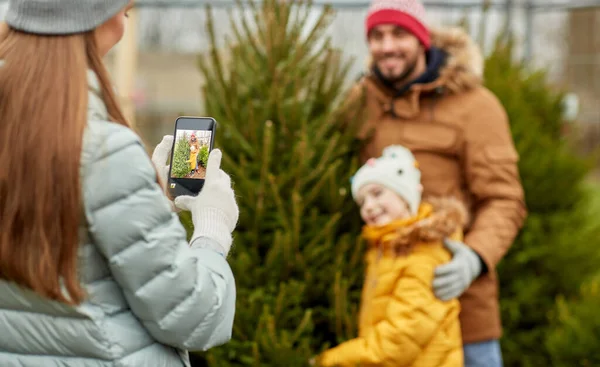 家族が市場でクリスマスツリーを撮影し — ストック写真