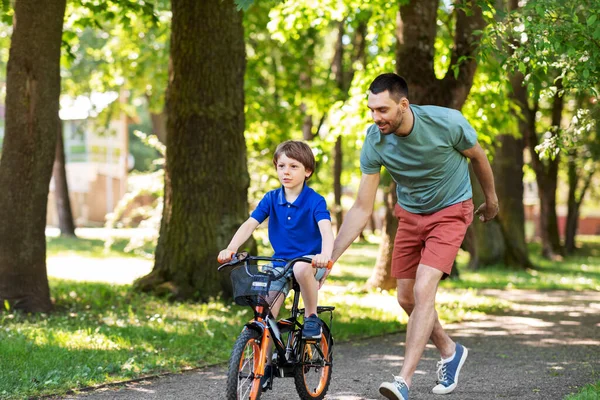 パークで自転車に乗ることを息子に教える父親 — ストック写真