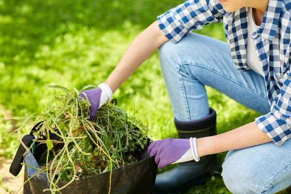 Mulher com saco cheio de ervas daninhas no jardim de verão — Fotografia de Stock
