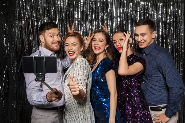 Amigos felices tomando selfie por teléfono inteligente en la fiesta — Foto de Stock