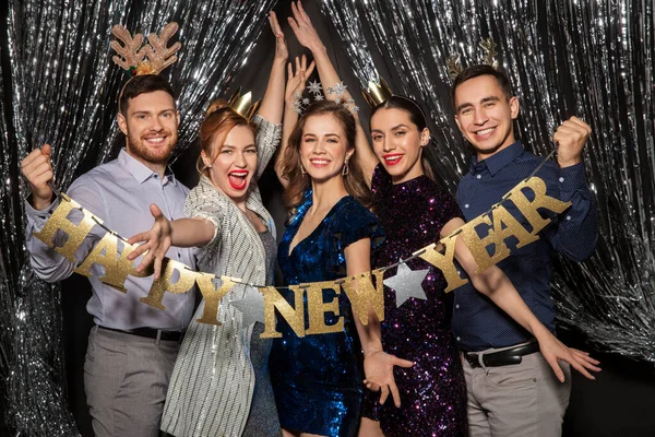 Amigos felizes posando com banner de ano novo — Fotografia de Stock