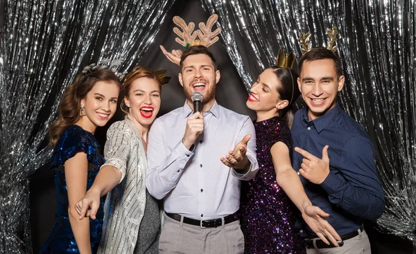 Amigos con micrófono cantando en la fiesta de Navidad —  Fotos de Stock