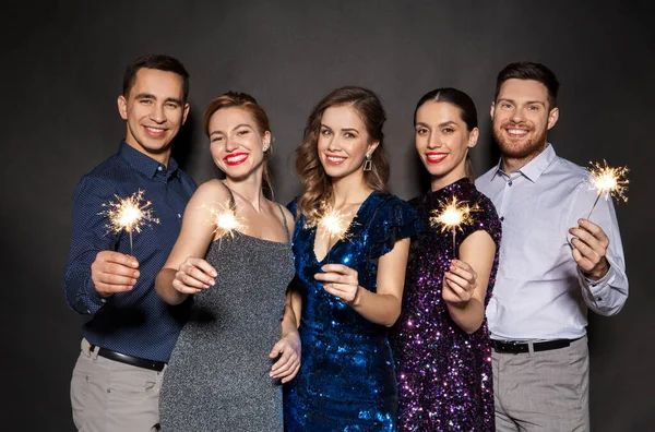 Amigos felizes em roupas de festa com sparklers — Fotografia de Stock
