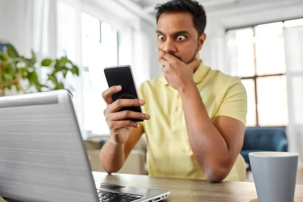 Geschokt indiaanse man met smartphone werken thuis — Stockfoto