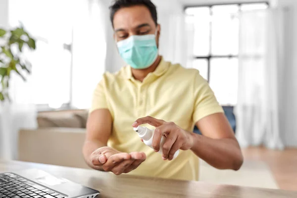 Muž v masce pomocí dezinfekčního prostředku na ruce doma — Stock fotografie