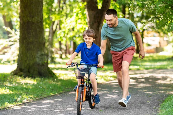 Padre enseñando a su hijo a montar en bicicleta en el parque — Foto de Stock