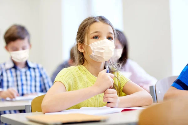 Piccola studentessa in maschera sulla lezione a scuola — Foto Stock