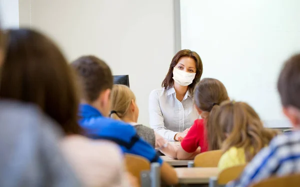 Professor em máscara com grupo de crianças na escola — Fotografia de Stock