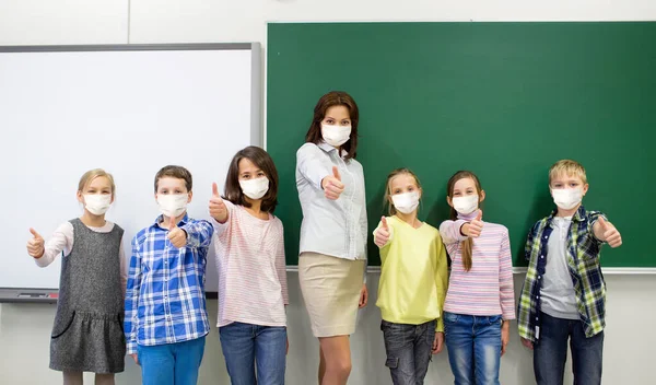Estudiantes y maestro de escuela en máscara mostrar pulgares hacia arriba —  Fotos de Stock