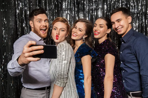 Amigos felices tomando selfie por teléfono inteligente en la fiesta — Foto de Stock