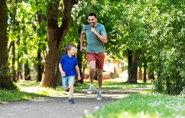 Šťastný otec a syn soutěžit v běhu v parku — Stock fotografie