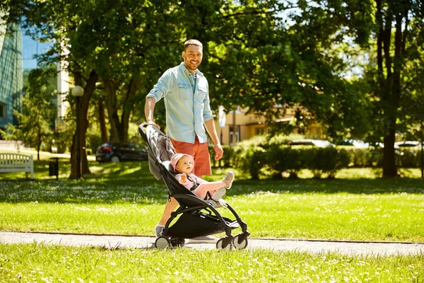 Glücklicher Vater mit Kind im Kinderwagen im Sommerpark — Stockfoto