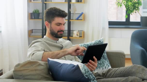 Χαμογελαστός άνθρωπος με tablet υπολογιστή στο σπίτι — Αρχείο Βίντεο
