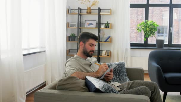 Hombre escribiendo a cuaderno y pensando en casa — Vídeos de Stock