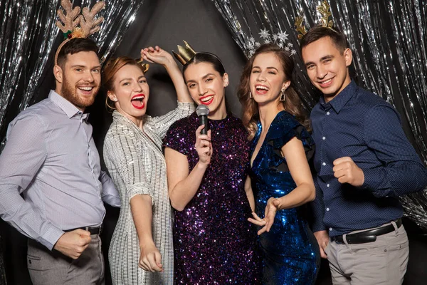 Amigos con micrófono cantando en la fiesta de Navidad —  Fotos de Stock