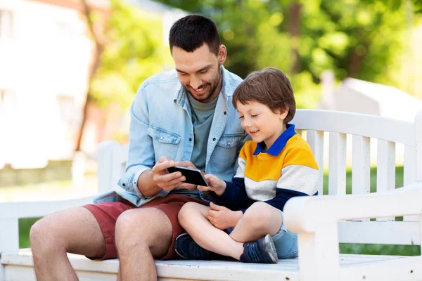 Vader en zoon met smartphone op park — Stockfoto