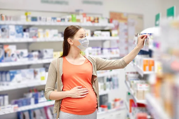 Mujer embarazada en la máscara compra medicamentos en la farmacia — Foto de Stock