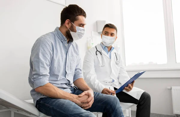 Médico do sexo masculino e paciente em máscaras no hospital — Fotografia de Stock