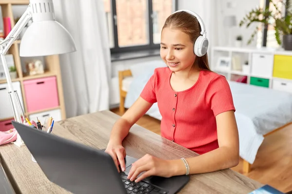 Menina em fones de ouvido com computador portátil em casa — Fotografia de Stock