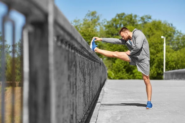 Man stretching leg on bridge — Stock Photo, Image
