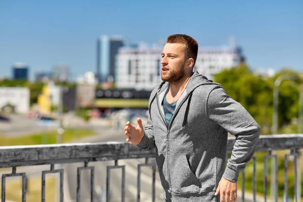 Glücklicher junger Mann läuft über Stadtbrücke — Stockfoto