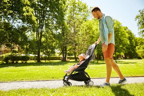Счастливый отец с ребенком в коляске в летнем парке — стоковое фото