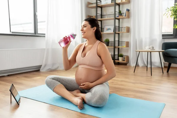 Mujer embarazada bebiendo agua después del yoga en casa —  Fotos de Stock