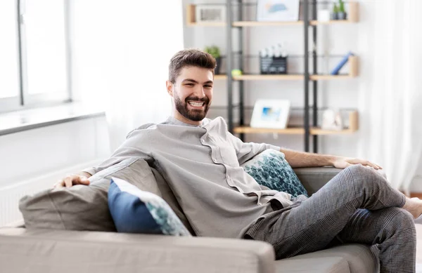 Feliz sorrindo homem sentado no sofá em casa — Fotografia de Stock