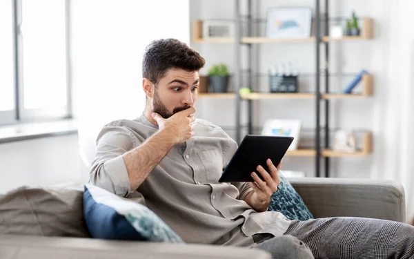 Shocked man with tablet computer at home — Stock Photo, Image